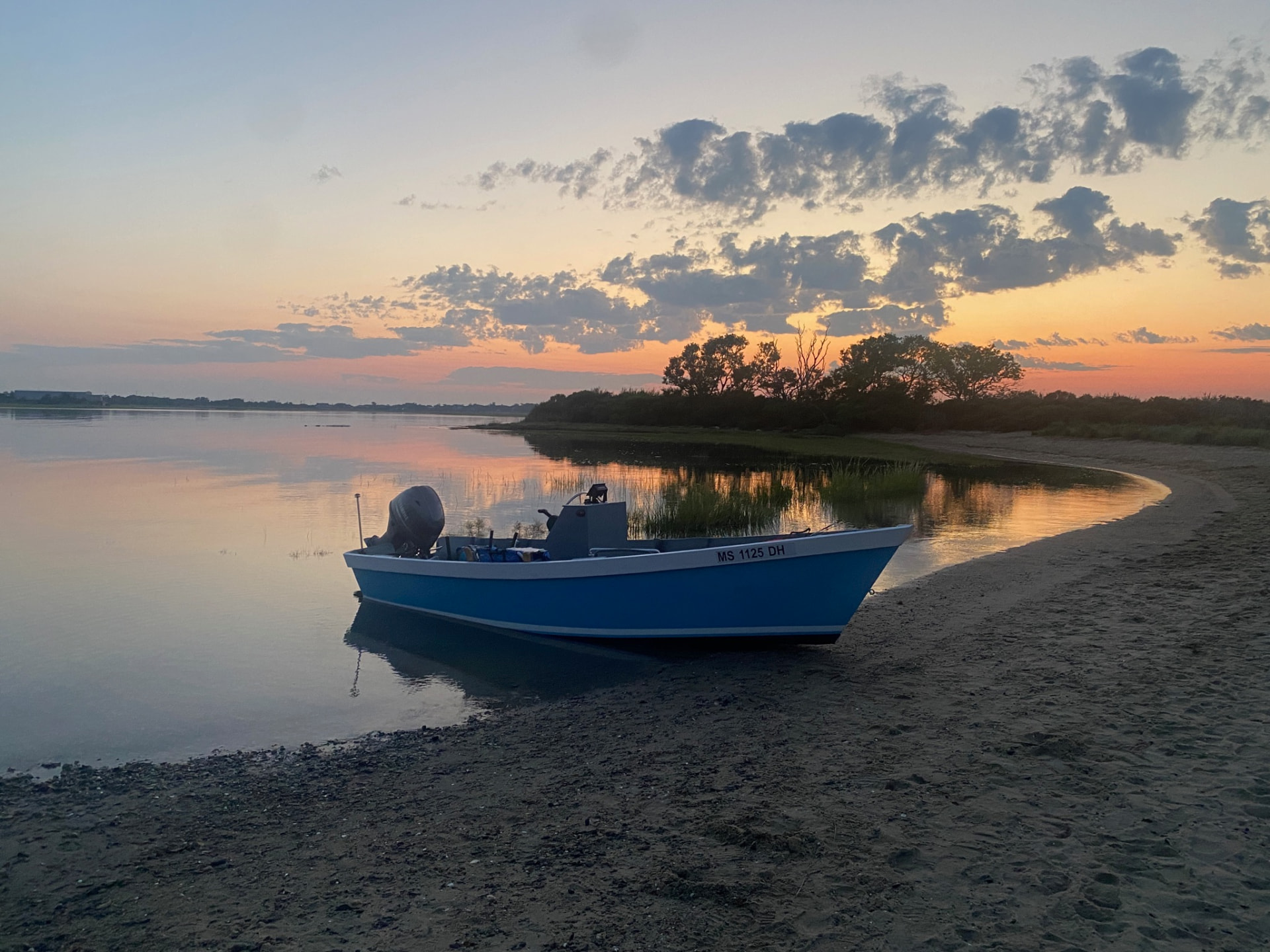 Blue Lady Bug skiff on calm water at sunset