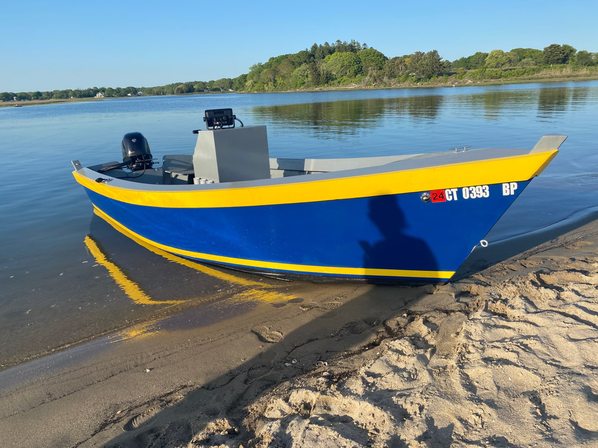 Blue and yellow Lady Bug skiff at the water's edge