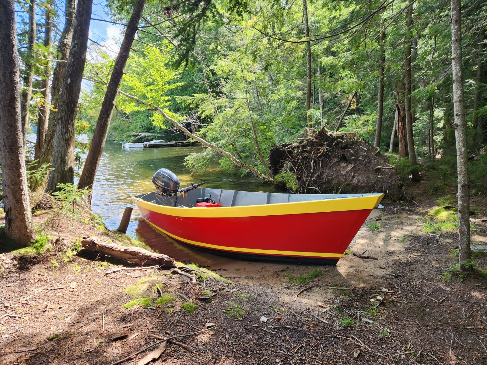 Red and yellow Lady Bug skiff on a wooded lakeshore